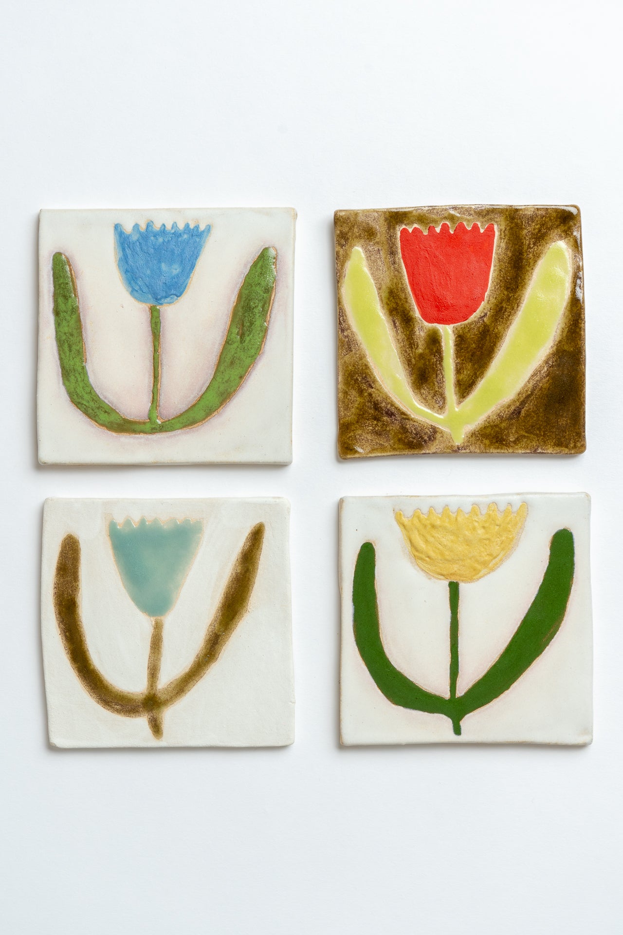 Four square tiles with colorful floral designs on a white background