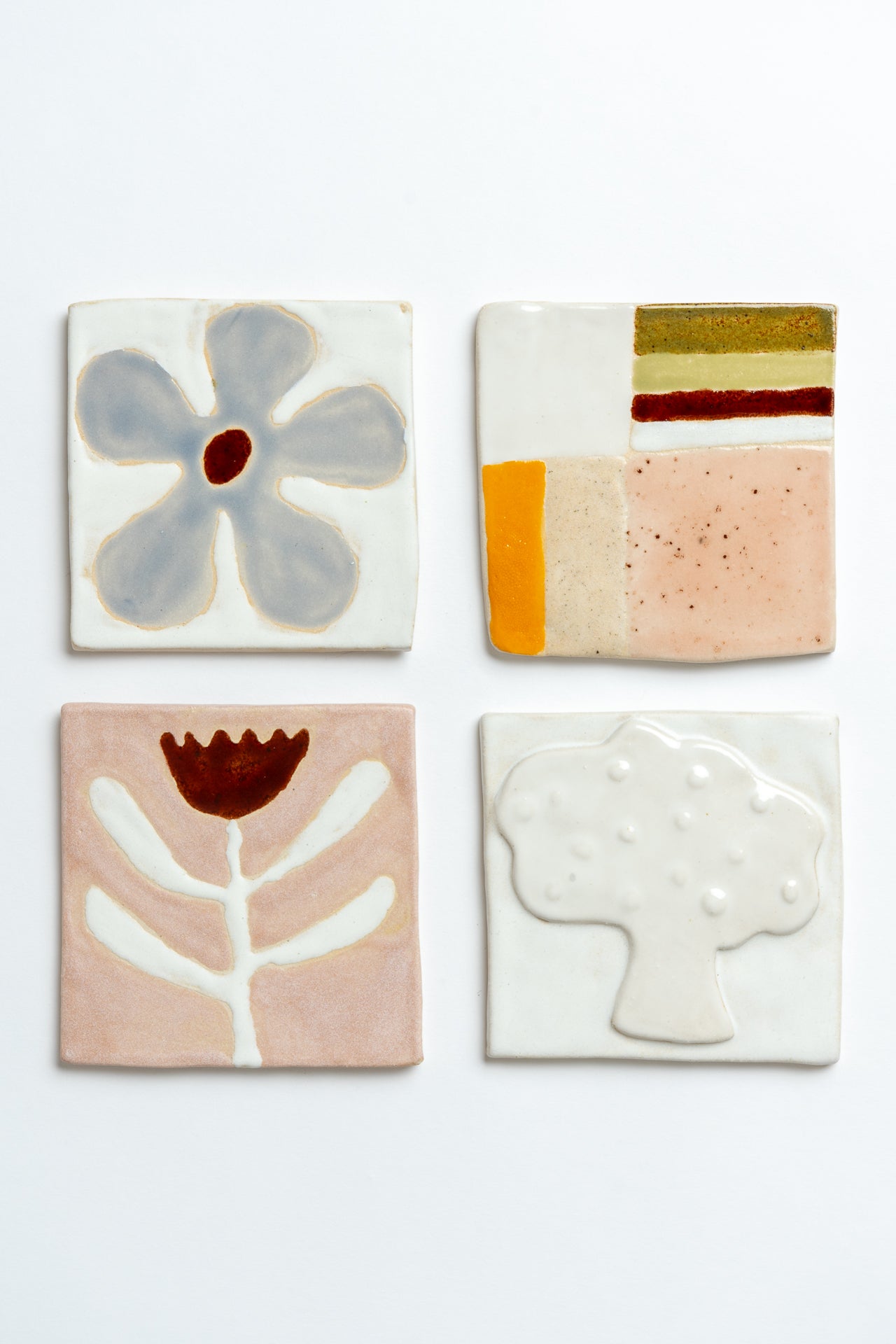 Four ceramic tiles with abstract designs on a white background handmade by contemporary British ceramicist Studio Alice Johnson in collaboration with MIMMO Studios