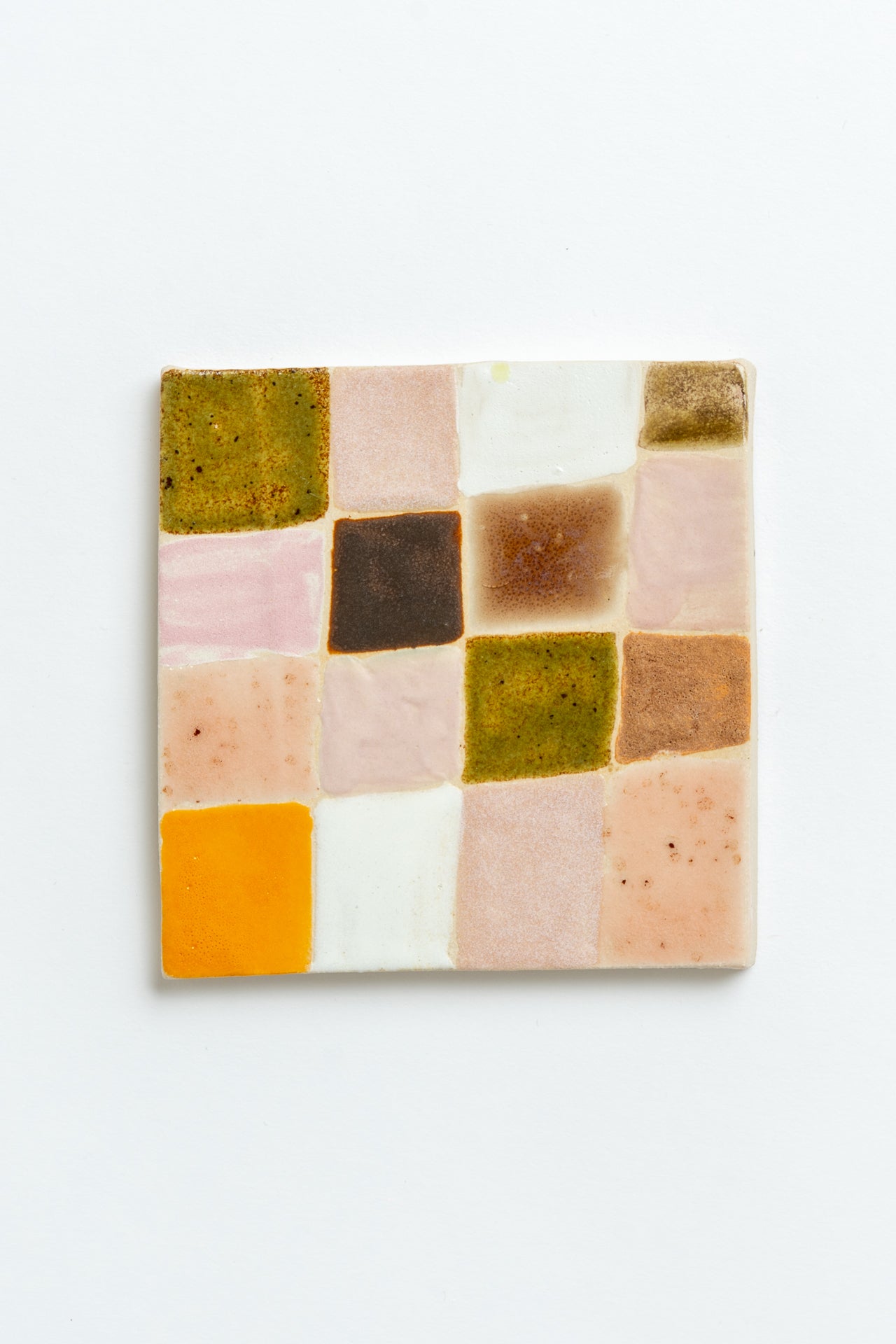 Square ceramic tile with a patchwork of multicolored squares on a white background handmade by contemporary British ceramicist Studio Alice Johnson in collaboration with MIMMO Studios
