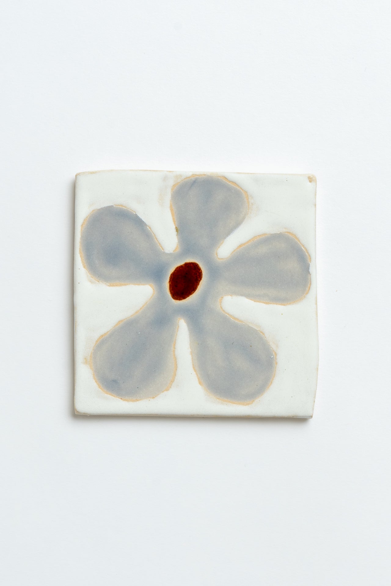 Ceramic tile with a blue flower design on a white background handmade by contemporary British ceramicist Studio Alice Johnson in collaboration with MIMMO Studios