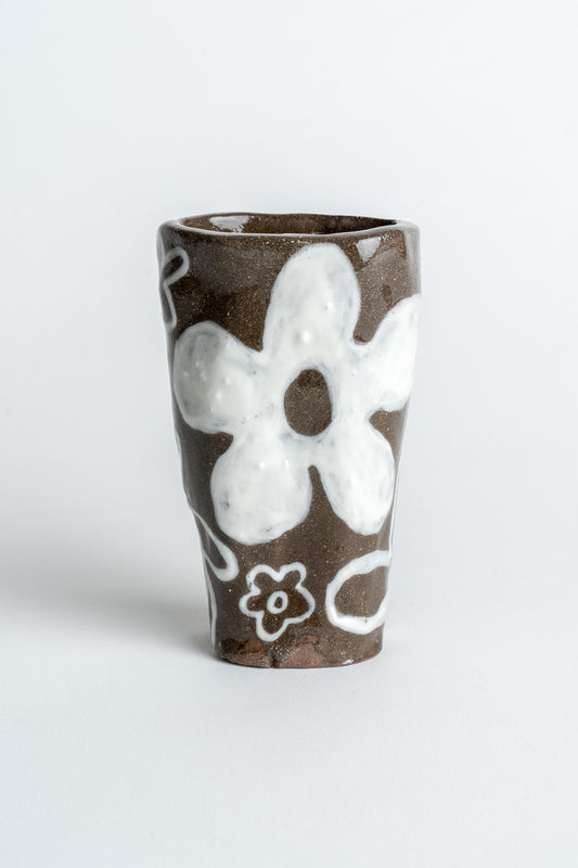 A hand painted ceramic vase with a floral design, featuring a brown body and white flowers.