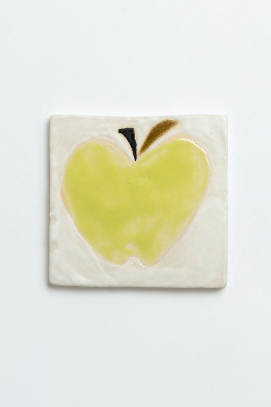 Ceramic tile with a green apple design on a white background handmade by contemporary British ceramicist Studio Alice Johnson in collaboration with MIMMO Studios