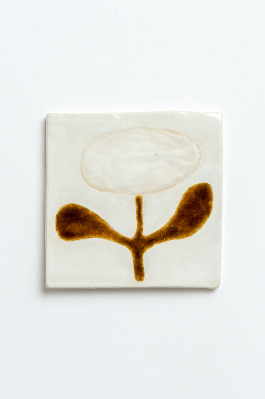 Square ceramic tile with a brown and white floral design on a white background Two square tiles with spiral patterns on a white background handmade by contemporary British ceramicist Studio Alice Johnson