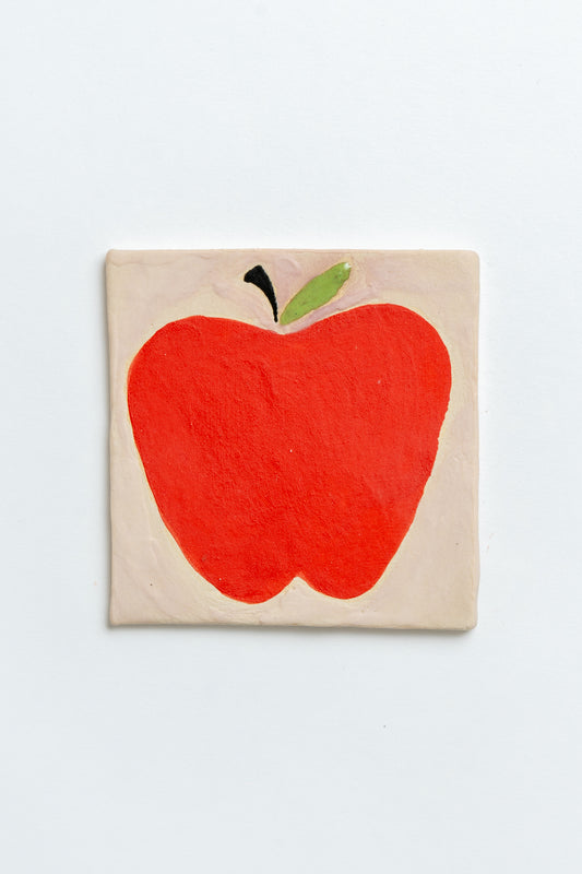 Ceramic tile with a red apple design on a white background Two square tiles with spiral patterns on a white background handmade by contemporary British ceramicist Studio Alice Johnson