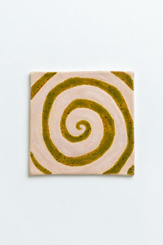 Square tile with a green spiral design on a light grey background Two square tiles with spiral patterns on a white background handmade by contemporary British ceramicist Studio Alice Johnson