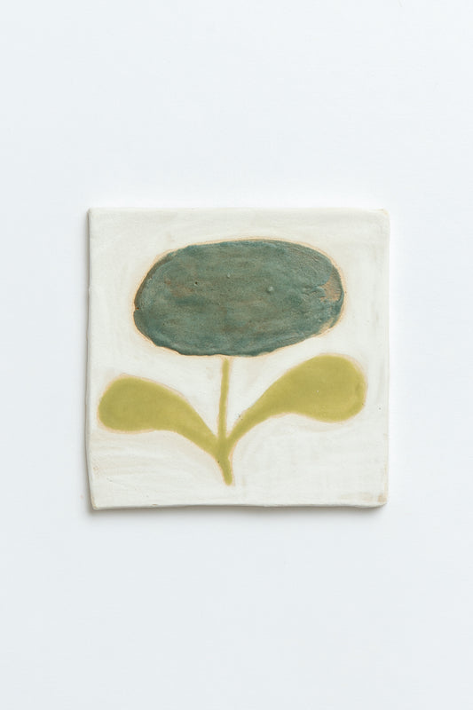 Ceramic tile with a green flower design on a white background by contemporary British ceramicist Studio Alice Johnson
