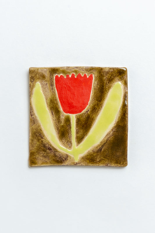 Ceramic tile with a red tulip flower design on a white background by contemporary British ceramicist Studio Alice Johnson