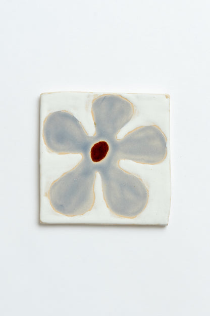 Ceramic tile with a blue flower design on a white background handmade by contemporary British ceramicist Studio Alice Johnson in collaboration with MIMMO Studios
