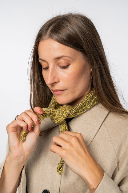 Woman adjusting a green knitted scarf against a white background