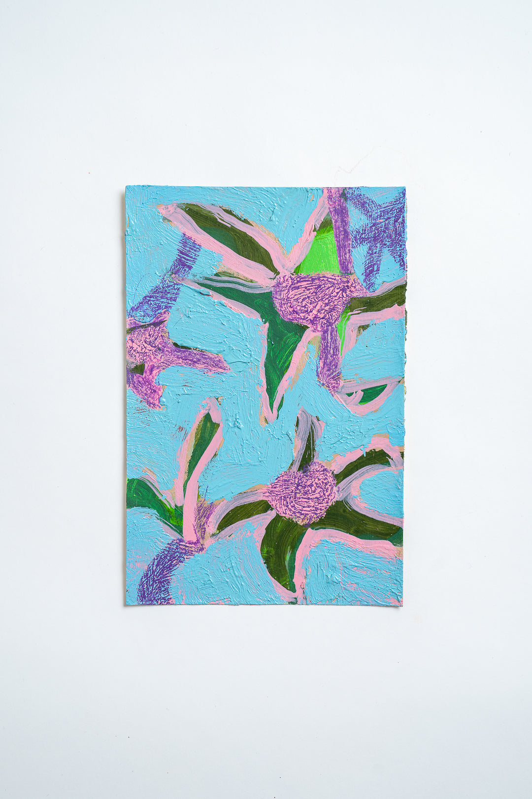 An abstract floral oil painting featuring textured purple flowers with green leaves on a light blue background, displayed against a clean white wall.