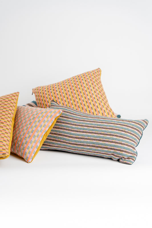 A collection of rectangular and square bolster cushions with a geometric pattern, featuring colors such as orange, gray, and blue.